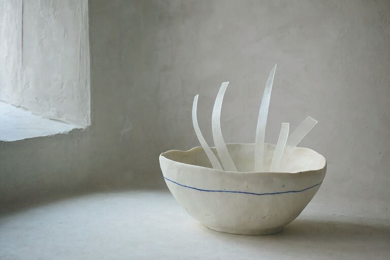 A handmade porcelain bowl holding five translucent ribbons, representing caption lines lifted out of a video player